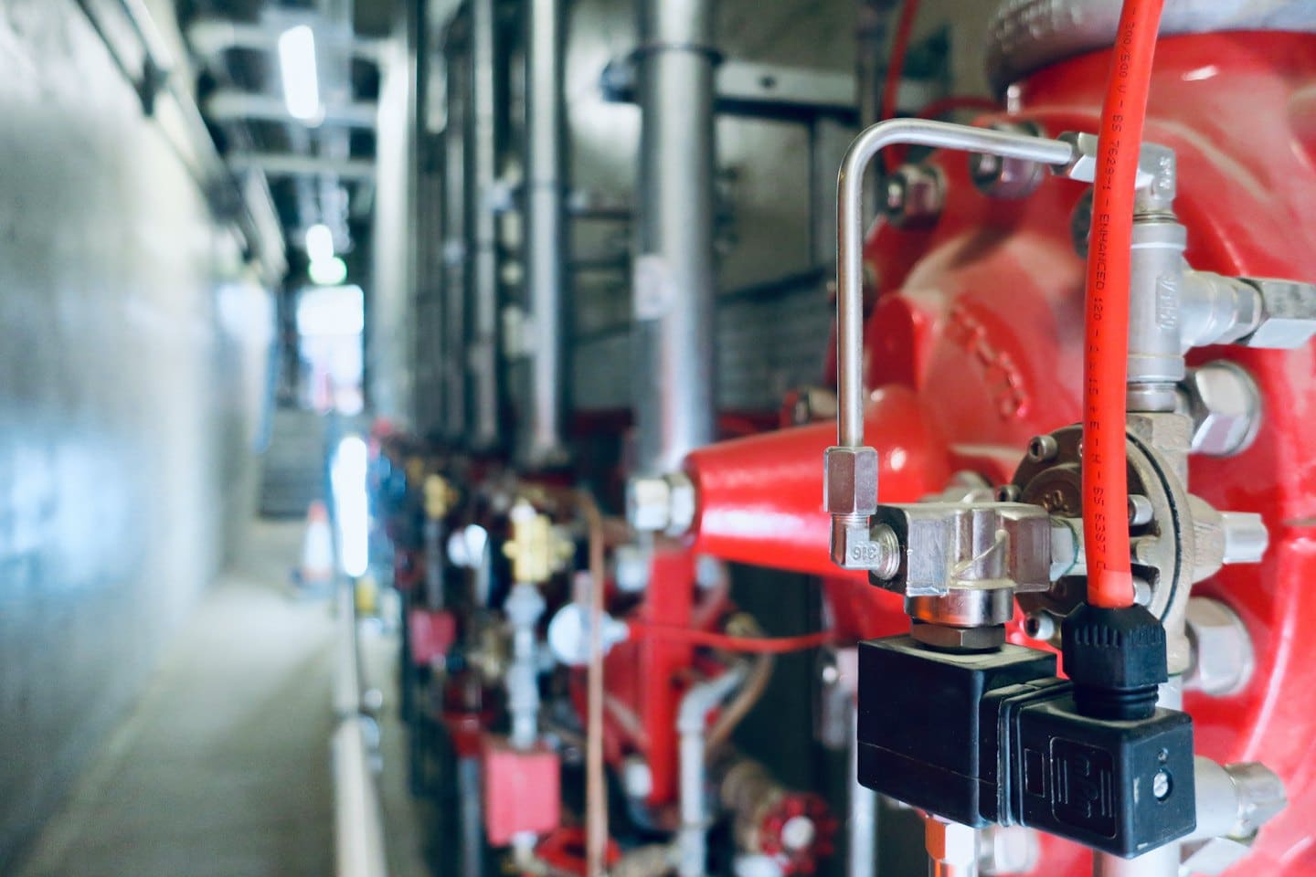 Red industrial pipes and control systems in a utility space.